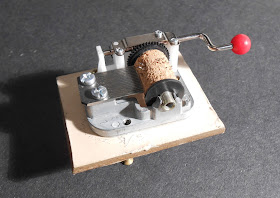 A small object topped with what appears to be the mechanical element of a music box.