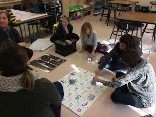 Teachers sitting on floor around an alphabet grid playing with Blue Bots