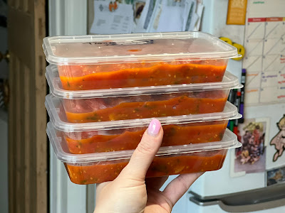 A stack of four tupperware tubs of tomato base for pasta