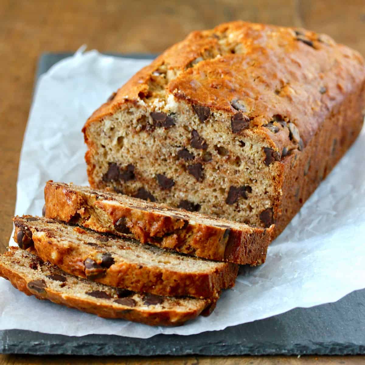 Browned Butter Chocolate Chip Banana Bread sliced on a piece of crumpled parchment paper.