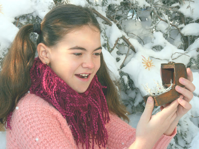 Smiling girl admiring snowflake jewelry inside a wooden jewelry box