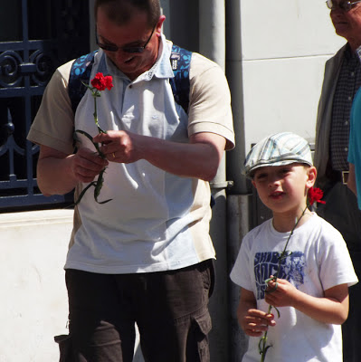 pai e filho na rua cada um segurando um cravo vermelho