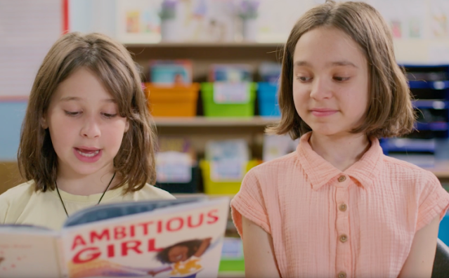Two girls read the picture book Ambitious Girl
