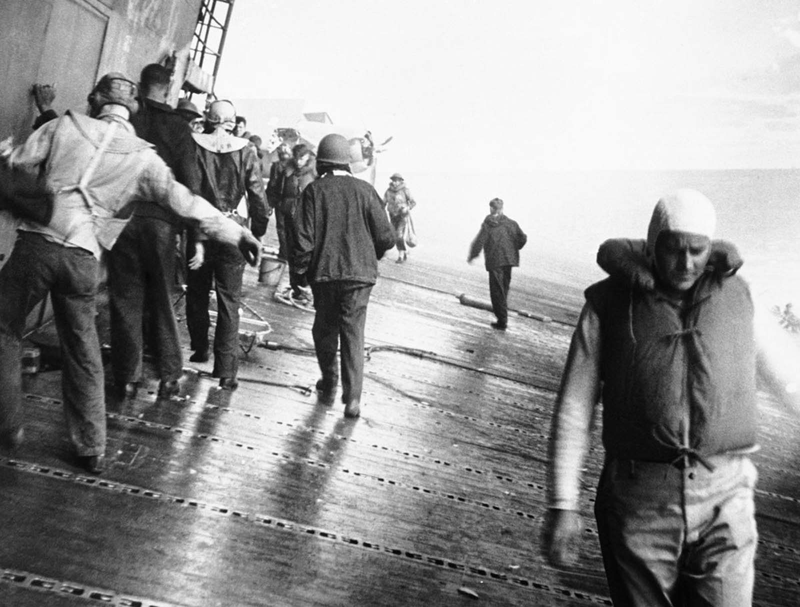 Tripulantes do USS Yorktown escolhem seu caminho ao longo do convés de vôo inclinado do porta-aviões, conforme o navio alista, indo em direção a seções danificadas para ver se eles podem consertar o navio aleijado, em junho de 1942.