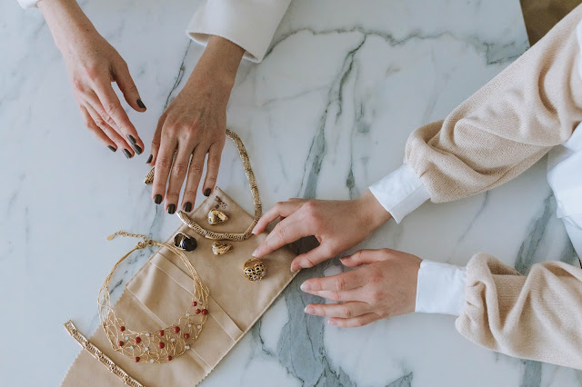 Two pairs of hands inspecting jewelry.