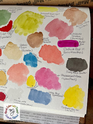 A closeup of a chaotic watercolor color swatching sketchbook page.