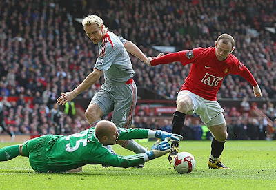 Pepe Reina of Liverpool dives to make a save at the feet of Wayne Rooney of Manchester United.