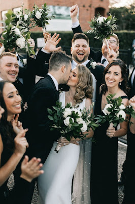 bride and groom kissing with bridal party cheering
