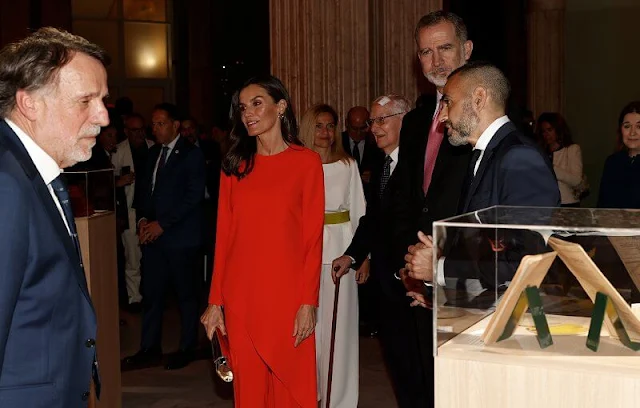 Queen Letizia wore a red coral asymmetric top and coral trousers by Zara. CXC gold earrings. Magrit gold leather pumps