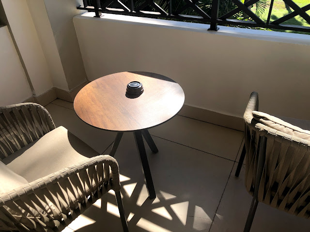 A balcony with cushioned wicker chairs and a table