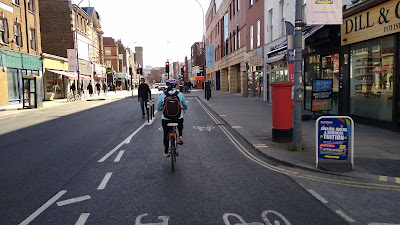 A view of a street. There are light coloured footways on both sides and a dark carriageway. The left side is is for general traffic and the right side is for 2-way cycling.