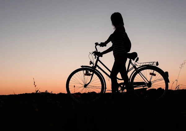 Silhueta de mulher andando de bicicleta. #PraCegoVer