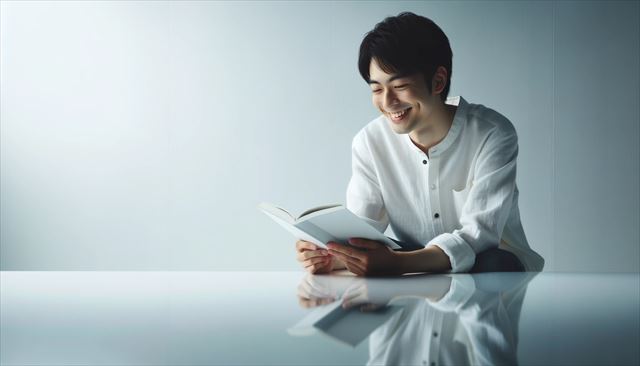 In a wide horizontal frame, the focus is on simplicity with a vast white canvas. Breaking the monotony is a young Japanese man, reading and smiling contentedly. The soft lighting introduces delicate reflections and shadows.