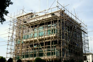 Image of a small house in Hong Kong surrounded with bamboo scaffolding for the workers to walk on.