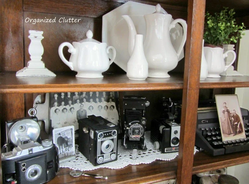 Cameras, Ironstone, & Typewriter Displayed in China Cabinet www.organizedclutterqueen.blogspot.com