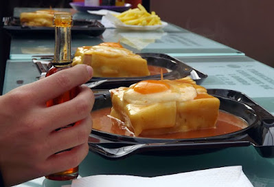 Pratos com sanduiches francesinhas e mão segurando um vidro com pimenta