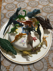 a birthday cake covered in toy dinosaurs 