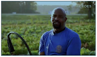 Rev. Richard Joyner smiles at camera while standing in a field of healthy crops