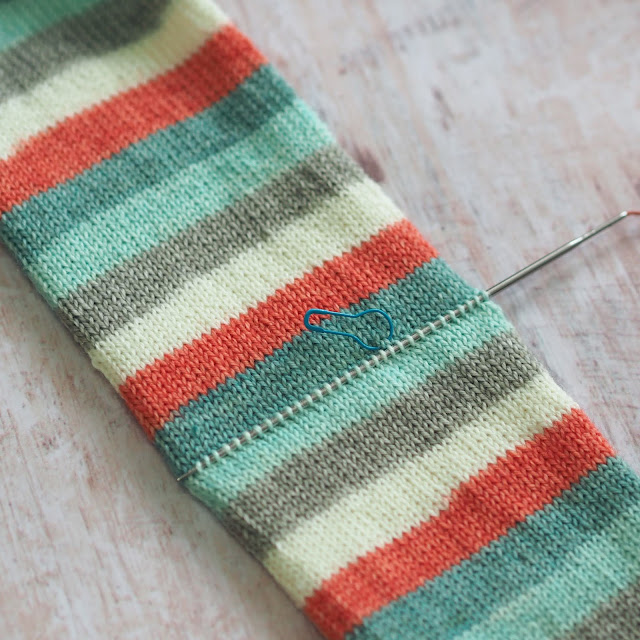 Blue, white and coral sock tube with one needle picking up stitches