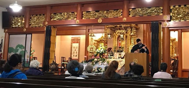 Buddhist Altar with people sitting in pews and minister playing music