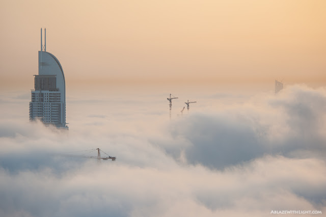 Photo of the building under construction and some tower cranes above the fog