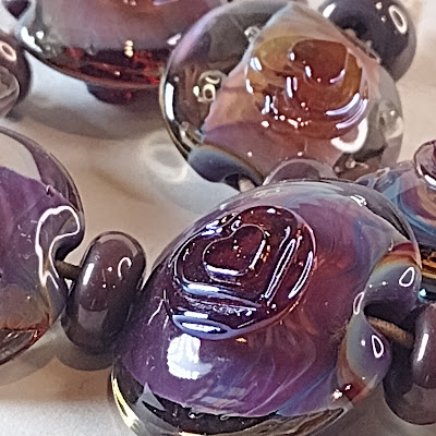 purple lampwork lrntil shaped beads with shimmering heart shaped dots