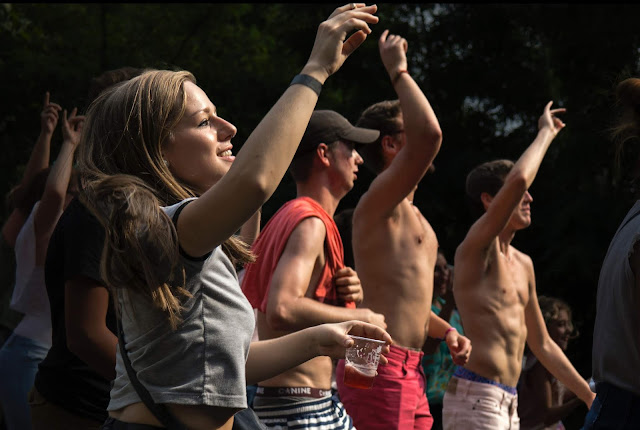 Woman holding glass hands in air with other people dancing