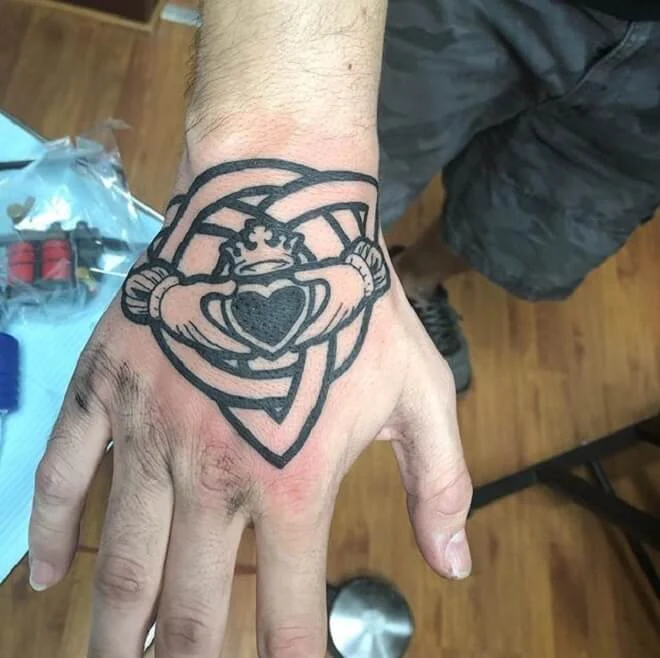 Fotografía de un tatuaje del anillo de claddagh en la mano de un joven