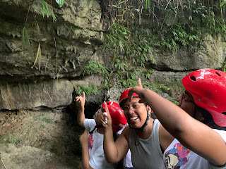 Un grupo de amigas emocionadas camina por los senderos del bosque, apuntando hacia un murciélago mientras se dirigen a las cavernas.