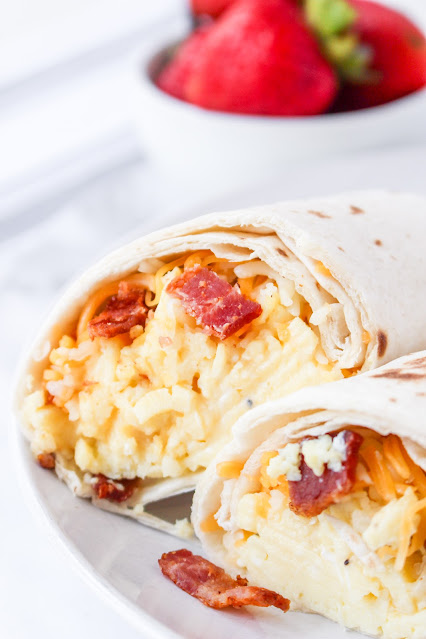 Bacon and Egg Breakfast Burrito cut in half on a white plate.