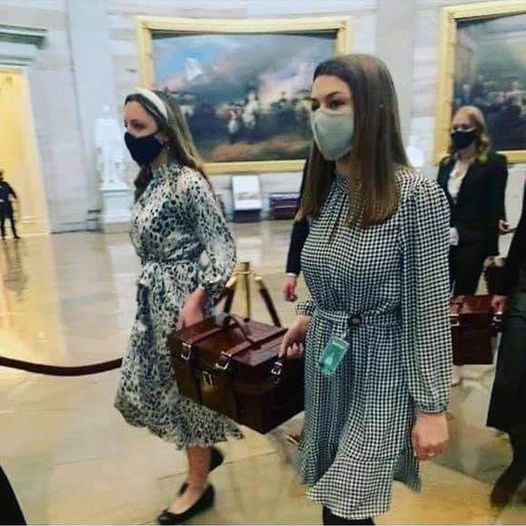 Image of congressional staffers, all women, carrying two Electoral College ballot boxes to safety.