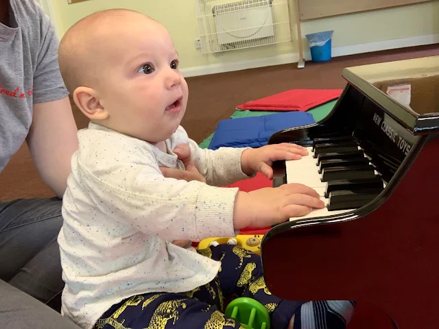 A baby boy playing a miniature piano