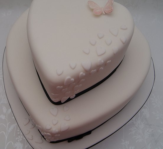 Two tier heart shaped wedding cake with mini hearts cascading over the edge