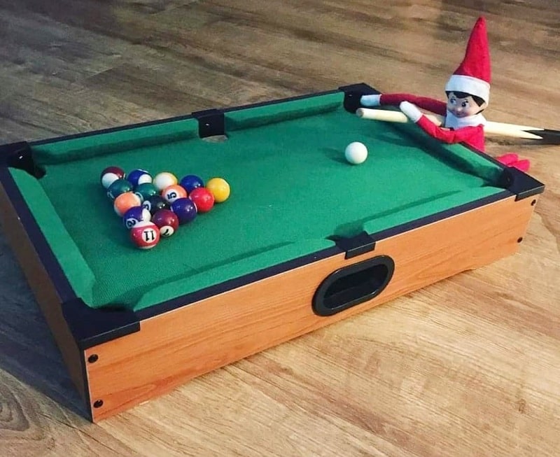 elf playing pool on mini pool table