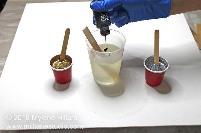 Pouring black resin pigment into a cup of mixed resin.