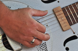 Close up of hand plucking resonator guitar strings