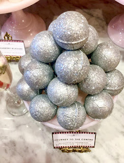 Spherical glittery bath oils in a clear glass bowl oon a bright background