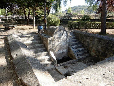 Fuente de piedra enmarcada por sendas escaleras que descienden hacia la zona de los cañosned