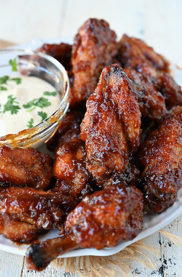 a close up of a white plate with honey bbq chicken wings