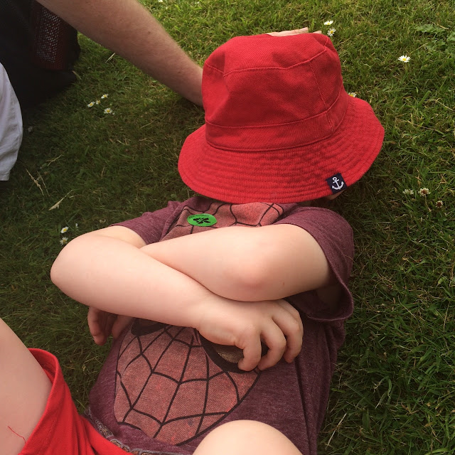 A little boy laying on the grass with his arms folded