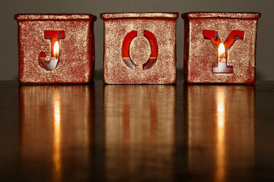 The word "Joy" spelled out using 3 candleholders.