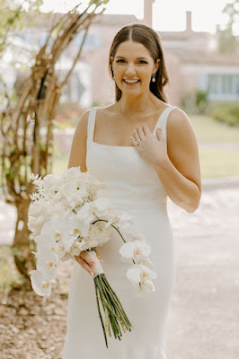 bride holding white orchid bouquet in white wedding dress