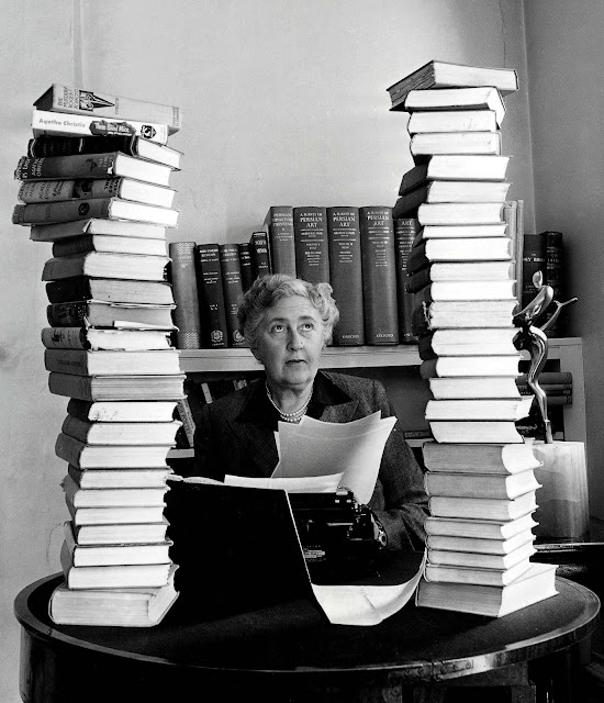 Agatha Christie surrounded by towering piles of her books