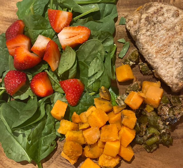 pork chop, sweet potato, okra, spinach and strawberry salad on plate