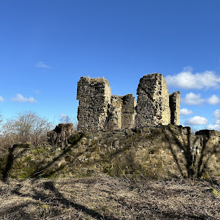 A view looking up from a lower wall to the crumbling walls of Lochore Castle.  There are shadows from the surrounding trees at angles to the walls.  Photograph by Kevin Nosferatu for the Skulferatu Project.