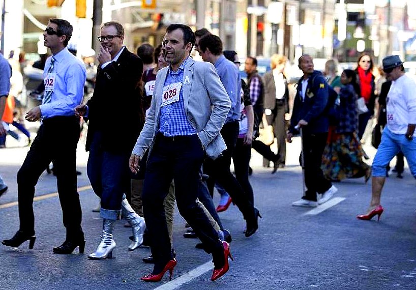 Men wearing red high-heel shoes march along the streets of El Paso, Oct.  16, 2012, in support of the Young Women's Christian Association's Walk a  Mile in Her Shoes event. The event