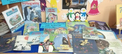Wystawka na stoliku niebieska bibuła książki o pingwinach praca plastyczna 3 pingwiny