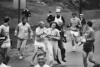 El 19 de Abril de 1967 en Massachusetts, se producía un hito en la historia del deporte, cuando Kathrine Switzer corrió de incognito la prohibida para mujeres "Maratón de Boston". Katherine era una joven estudiante de periodismo de la Universidad de Syracuse, que con solo 19 años se había transformado en una apasionada por el atletismo, más precisamente en carreras de fondo. Como la universidad no tenía equipo femenino de maratón, le pidió a su novio Tom, que entrenaba con vistas a los juegos olímpicos, que convenciera al entrenador de hombres, Arnie Briggs que la ayudara. Arnie era un experimentado corredor que tenía en su haber 15 maratones de Boston, la mas importante del mundo. Luego de los entrenamientos, Arnie le relataba a Katherine lo maravilloso de esa competencia y del prestigio que daba a sus participantes, hasta que un día le dijo "Entonces corrámosla". Arnie le explicó que era una competencia estrictamente masculina, pero ella no encontró en el reglamento ninguna referencia al género, se daba por sentado que las mujeres no podían correrla, por lo que decidió hacerlo de incógnito. Arnie la inscribió como "K Switzer" y le tocó el número "261", pasó 2 meses entrenando fuertemente llegando a marcas masculinas. La mañana de la carrera se presentó fresca y lluviosa, Katherine se comenzó a preparar, pero Arnie modificó sus planes, le hizo quitar el lápiz labial y ponerse un jogging sobre sus pantalones cortos, "no te das cuenta que si te descubren no te dejarán competir", no hay que llamar la atención. Katherine logró largar sin ser detectada, Arnie corría unos metros detrás para custodiarla. Pese a que un micro descapotable plagado de periodistas se movía a metros de los competidores nadie notó su presencia. Promediando la carrera, Arnie descubre que a la vera del camino estaba Jock Semple, un viejo veedor de la maratón con el brazalete azul de la BAA. En un segundo, Jack la descubrió, se interpuso en el camino de Katherine tomándola del cuello al grito de "Fuera de mi carrera y me dan esos números!!". Arnie se abalanzó sobre Jack liberando a Katherine, que continuó la competencia mientras ambos se quedaron forcejeando. El griterío dio tiempo a los periodistas para tomar fotos y registrar el incidente, Arnie, Jack y Tom cayeron al suelo. Minutos después los tres estaban nuevamente al mismo ritmo corriendo a la par. Cruzaron la meta exhaustos y nerviosos, la vida cambió para los tres, Arnie se convirtió en una celebridad, Tom fue separado del equipo olímpico y Katherine logró romper las barreras de la discriminación. El incidente tuvo repercusiones a nivel mundial y EEUU fue obligado a aceptar mujeres en las disciplinas olímpicas. El número "261" es utilizado como el símbolo de la igualdad en el deporte.