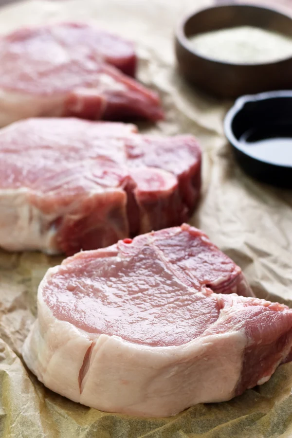 Close-up of raw pork chops, each 1 1/2 inches thick, prepared and waiting to be seasoned with ranch seasoning.