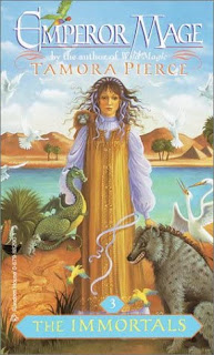 A teenage girl stands in front of a river, with a dragon, hyena, and various other animals arrayed around and on her.